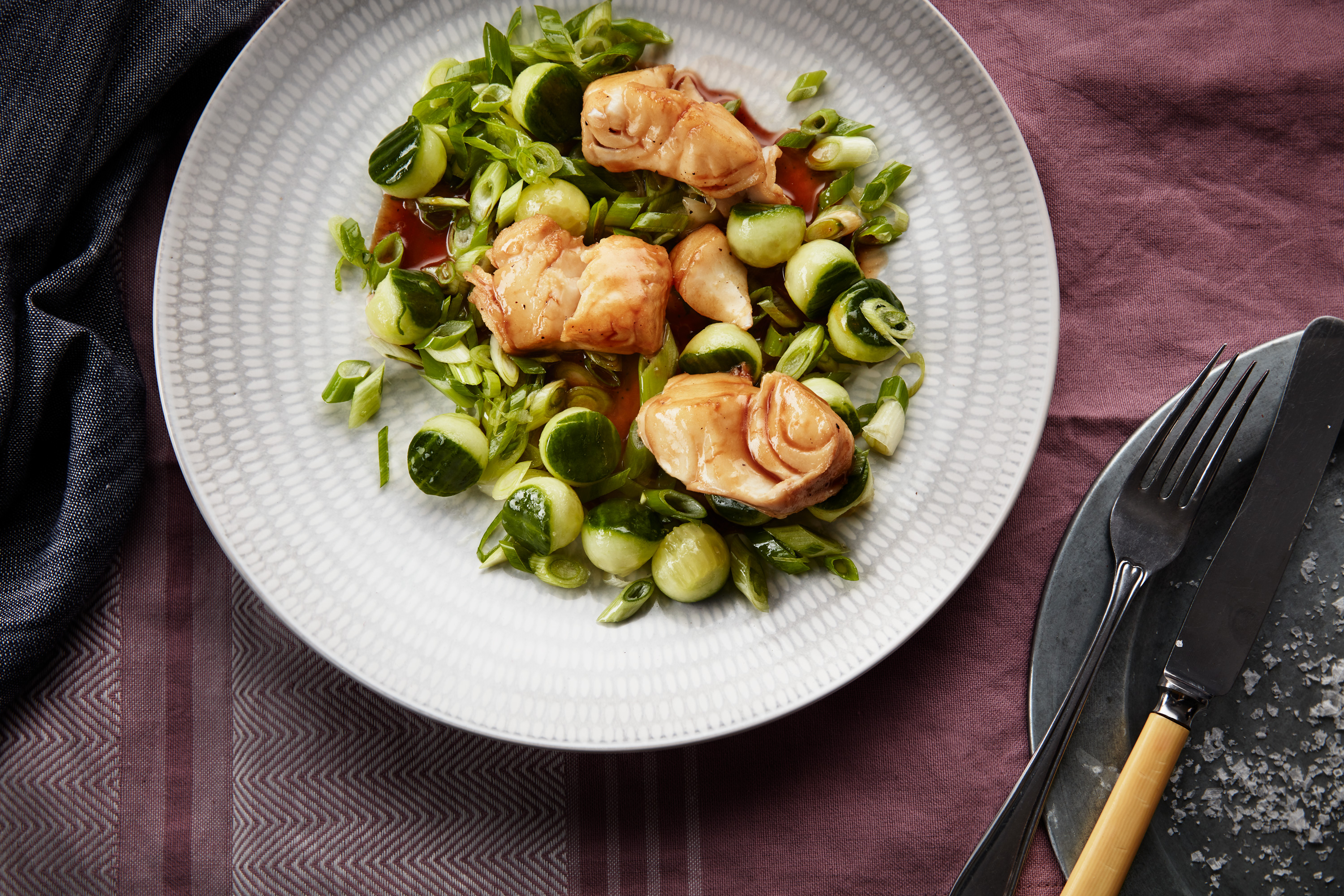 Stekt skrei  på en tellerken med vårløk og agurk