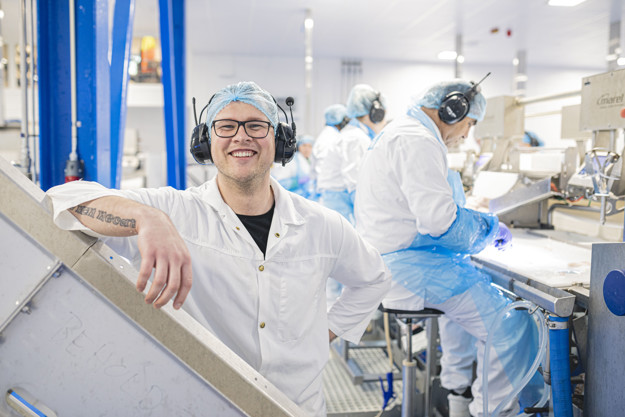 A man smiling with other men working behind him.