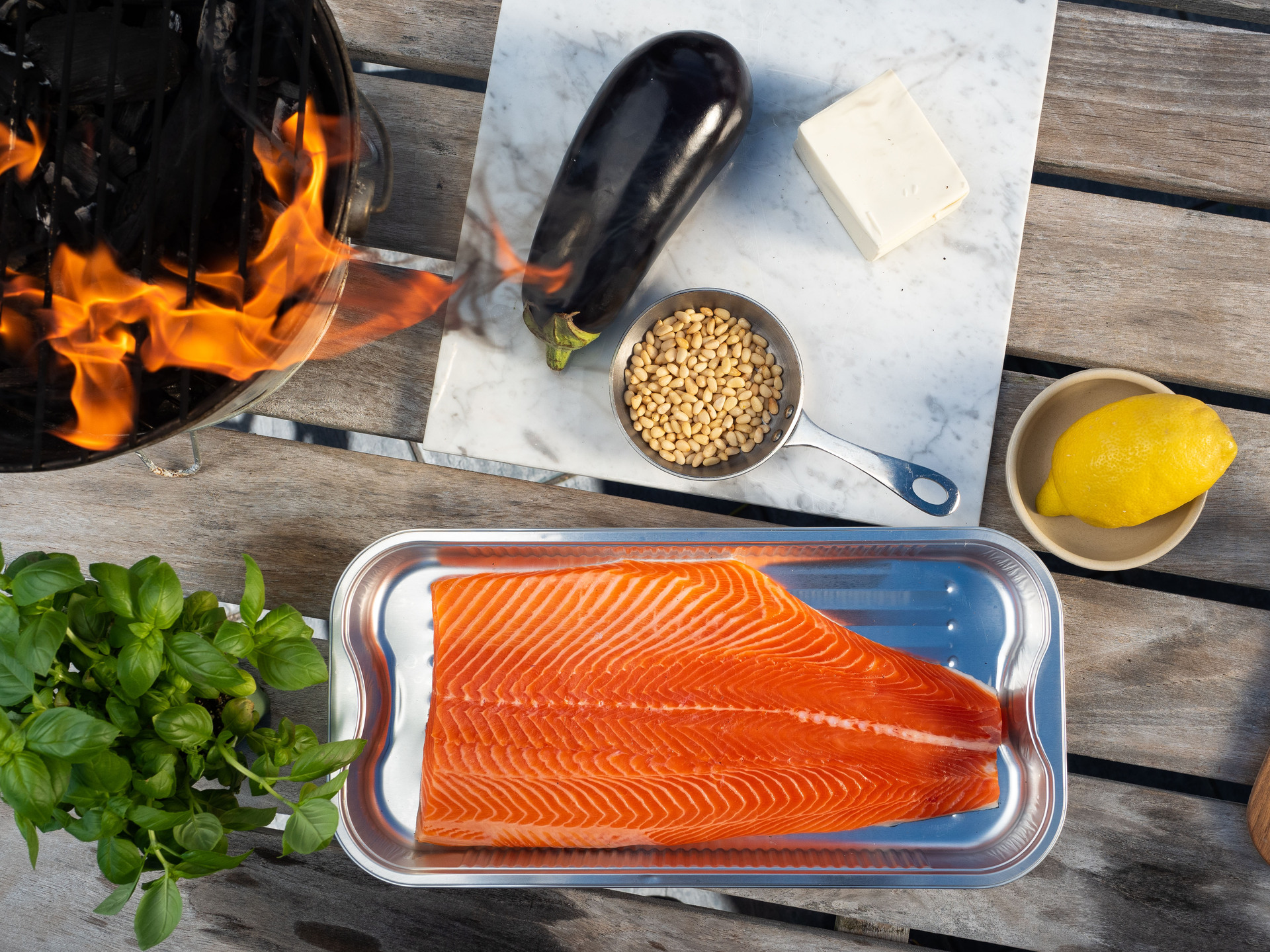 Trout fillet in aluminium tray- Surrounded by a BBQ and fresh produce