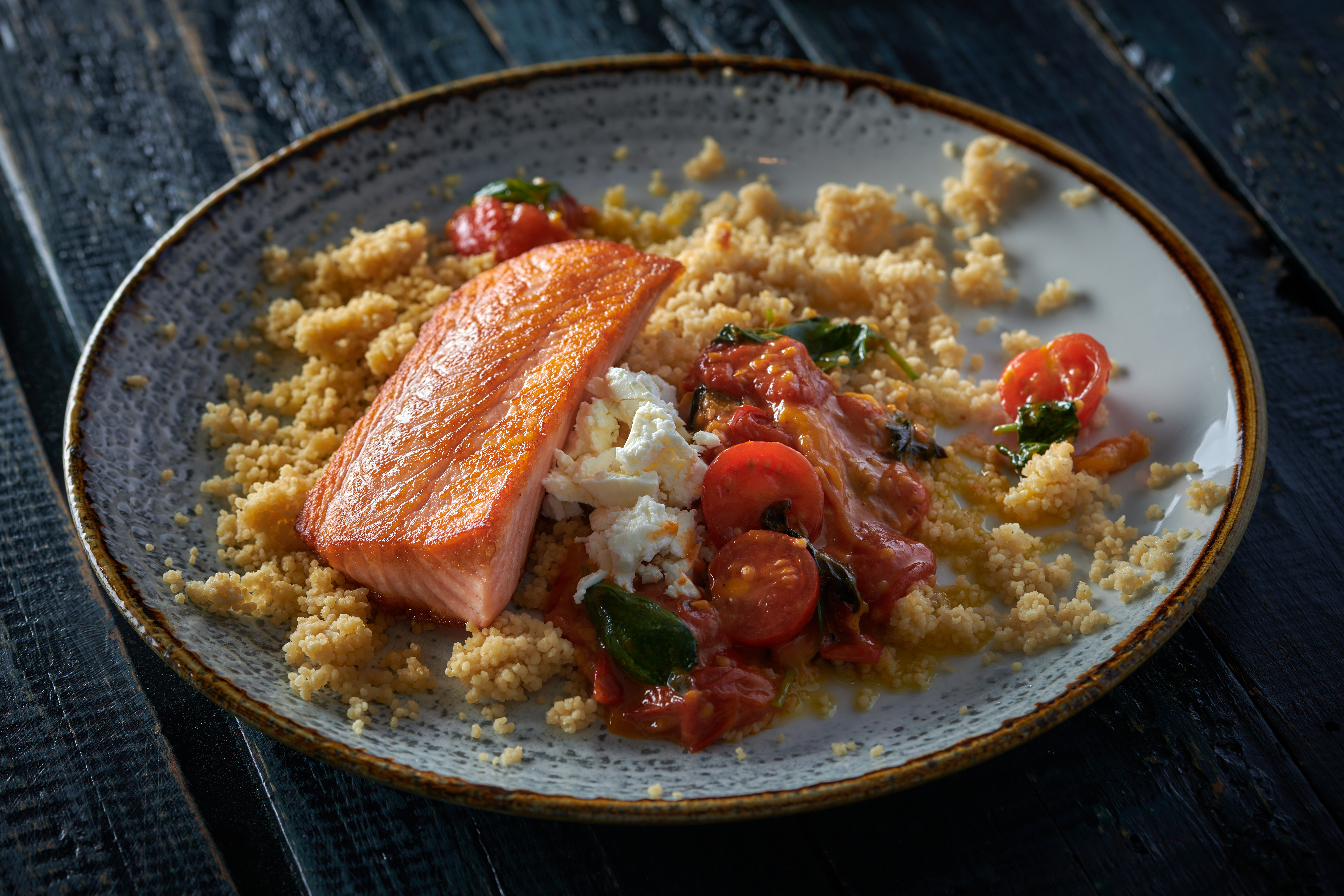 Laks med basilikumstomat og fetaost på tallerken med couscous